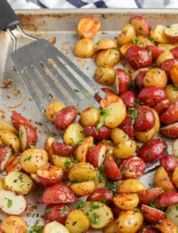 rosemary garlic roasted potatoes on a sheet pan with a spatula