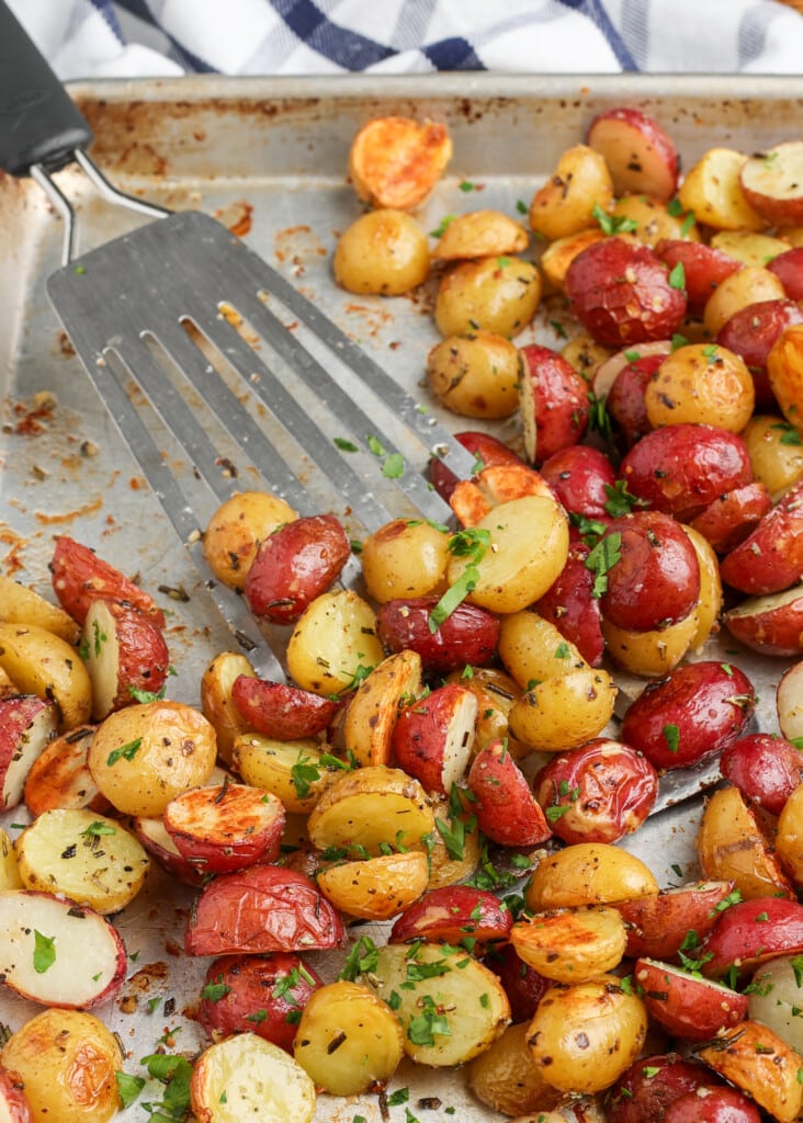 rosemary garlic roasted potatoes on a sheet pan with a spatula