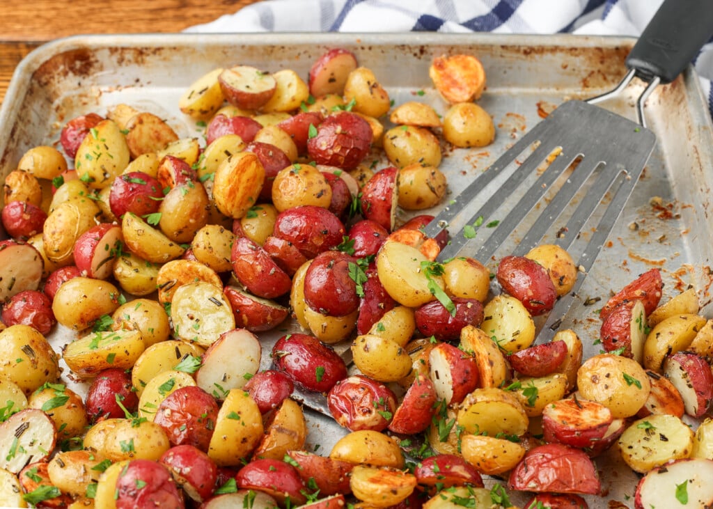 rosemary garlic roasted potatoes on a sheet pan with a spatula