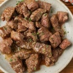 bite size pieces of steak on plate with butter sauce