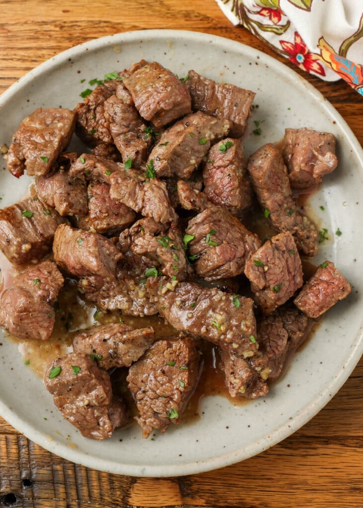 bite size pieces of steak on plate with butter sauce