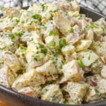 potato salad with ranch dressing in curvy black bowl on wooden table