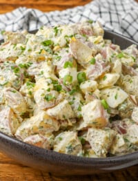 potato salad with ranch dressing in curvy black bowl on wooden table