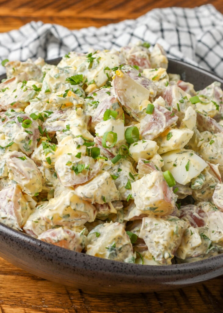 potato salad with ranch dressing in curvy black bowl on wooden table