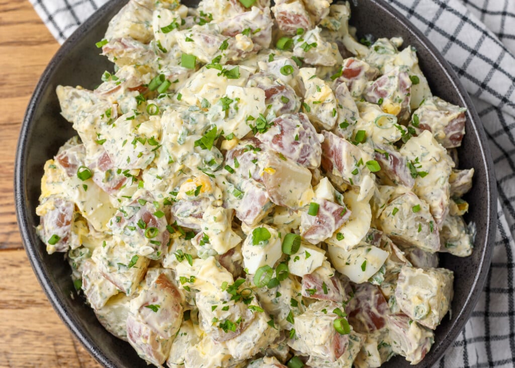 horizontal close up photo of potato salad in black bowl