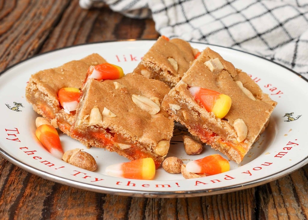 blondies with candy corn and peanuts on metal plate with plaid towel