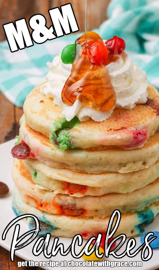 close up shot of M&M Pancakes with whipped cream and syrup stacked on plate