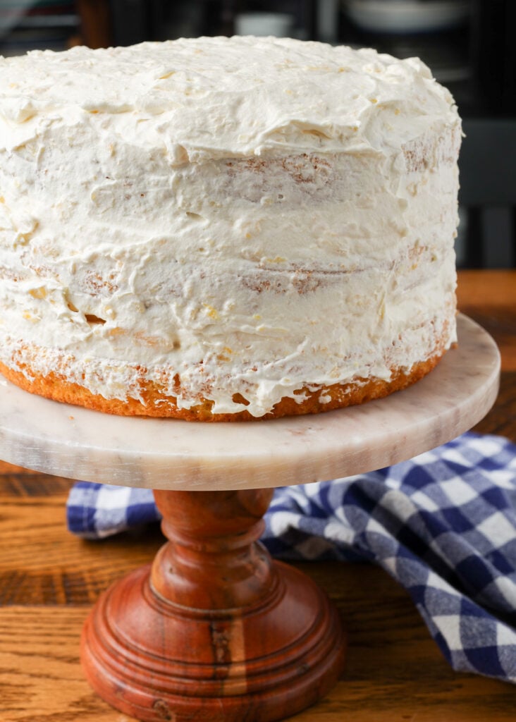 frosted pig pickin cake on wooden cake stand next to blue checkered napkin