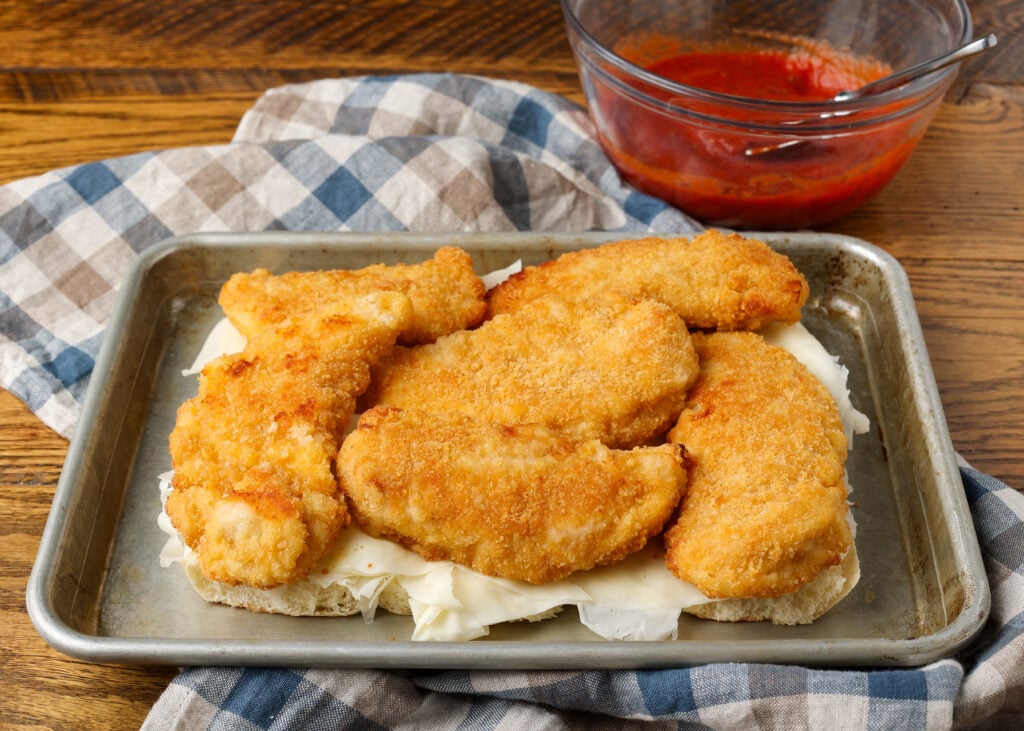 A horizontally aligned image of the chicken laid out across the tops of the cheese and marinara.