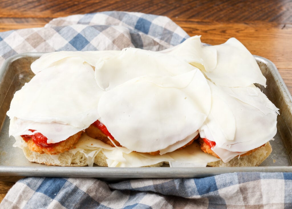 A horizontally aligned image of the final layer of cheese atop the chicken and marinara.