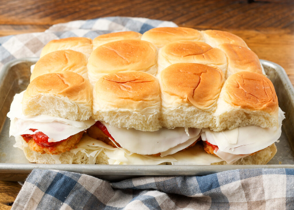 A horizontally aligned image of the sliders, completely layered and ready to be brushed with buttery goodness.