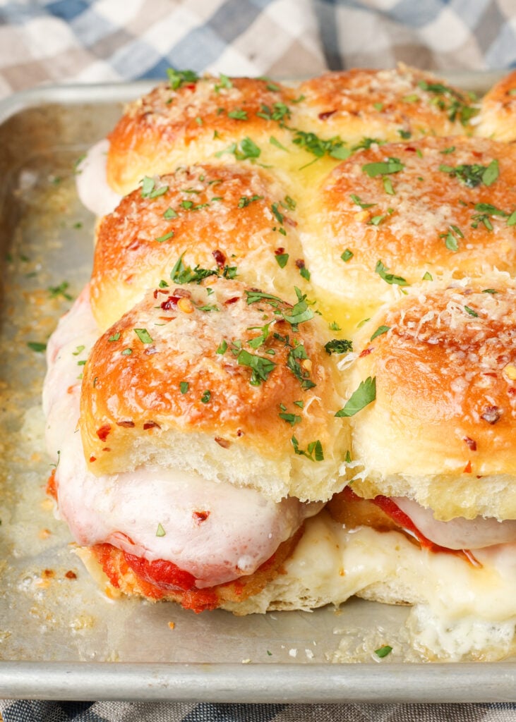 A vertically aligned image of the finished chicken parm sliders, showing melted, gooey provolone oozing out of the edge.