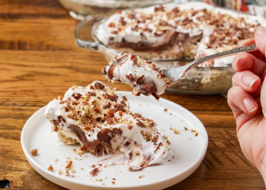 A horizontally aligned close up on a bite of possum pie on the fork, held aloft by a hand in the right hand side of the image.