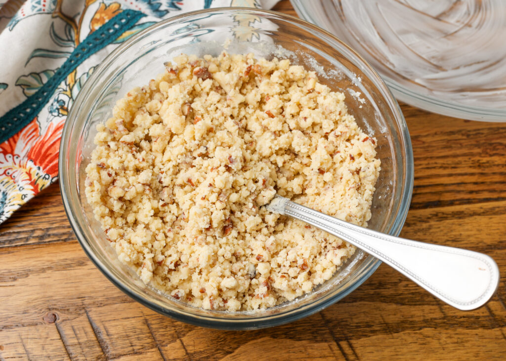 The crushed nuts, flour, butter have been mixed in a clear mixing bowl for the crusts.