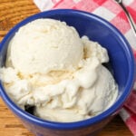 vanilla ice cream in a blue bowl next to a pink checked napkin